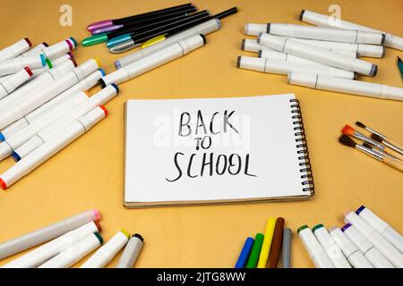 School background. A variety of school supplies and a notebook in the center with the inscription back to school Stock Photo