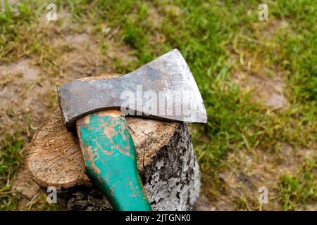 Defocus steel ax closeup. Big steel axe with wooden handle, metal ax for wood chopping. Green nature background. Forged axe it main accessory male, na Stock Photo