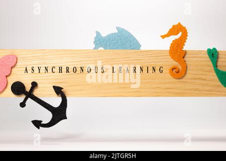 Asynchronous learning is written on a wooden patterned surface. Education and child psychology. Stock Photo
