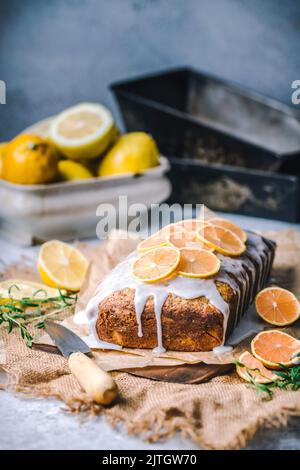 Lemon loaf poundcake topped with sliced pink lemons, loaf tins and lemon bowl in background Stock Photo