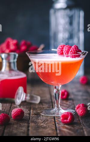 Side angle of Raspberry Cocktail in vintage glass with fresh raspberry garnish and raspberry syrup Stock Photo