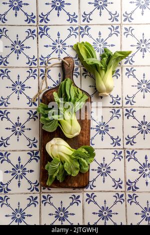 Fresh Bok Choy or Pak Choi (Chinese cabbage) on the dark wooden cutting board on stone background, organic vegetables Stock Photo