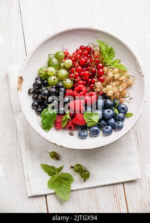 Fresh berries Mix with leaves in vintage ceramic colander on white background Stock Photo