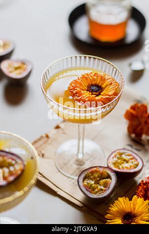 Passion fruit martini with edible flower in a coupe glass Stock Photo