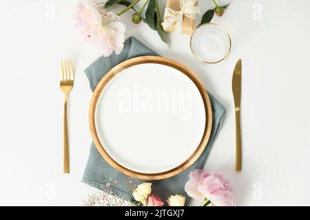 Beautiful table setting with golden cutlery and peony flowers, mock up, flat lay Stock Photo