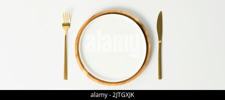 Stylish table setting, empty white and wood plates with fork and knife on white background, top view, flat lay Stock Photo