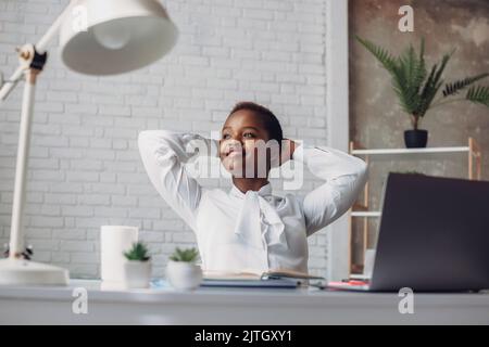 Portrait of pensive afro woman sitting at office desk while working with compute. Inspiration, idea. Internet information Stock Photo