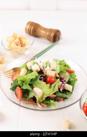 Fresh Salad with Cherry Tomatoes, Carrot, Romaine, Croutons, and Lettuce in a Plate on White Wooden Background Stock Photo