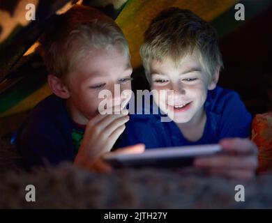 I wont tell on you if you let me play. siblings using a digital tablet under their fort at home. Stock Photo