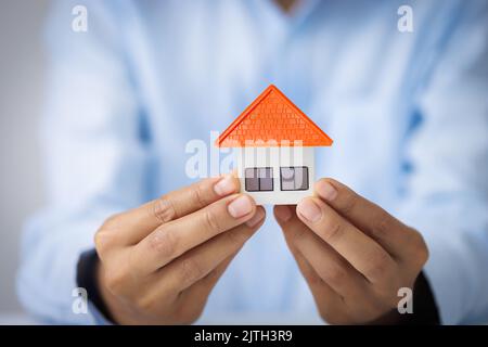 Your new house, woman hands holding a  model house. Mortgage property insurance dream moving home and real estate concept Stock Photo