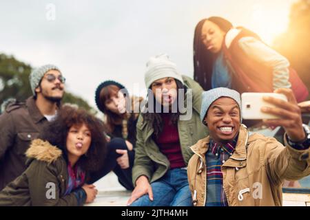 Young friends posing for a photo in front of a camera phone. Group of  multicultural friends having fun while hanging out together at night.  Generation Z friends making happy memories on the