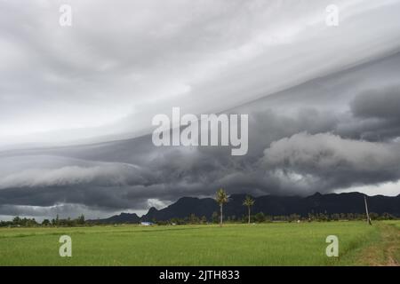 Gray Cumulonimbus cloud formations on sky above mountain, Nimbus moving with rice field,  Arcus cloud rolling in the storm with Appearance of rain Stock Photo