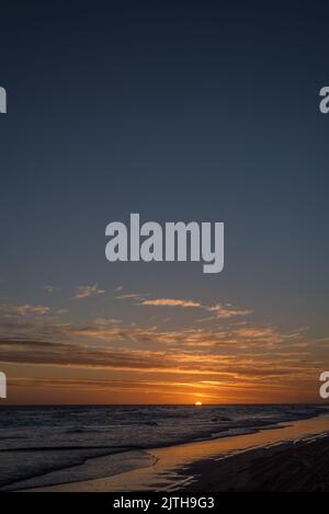 Portrait of dramatic sunset sky with clouds and reflection on the sea. Stock Photo