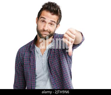 Sorry, thats just not good enough. Studio shot of a young man showing thumbs down against a white background. Stock Photo