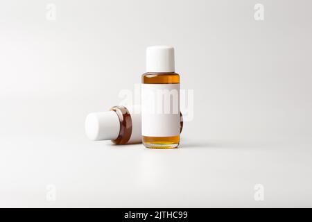 small oil bottles with white caps, with blank labels, mock-up template, isolated on neutral gray background Stock Photo