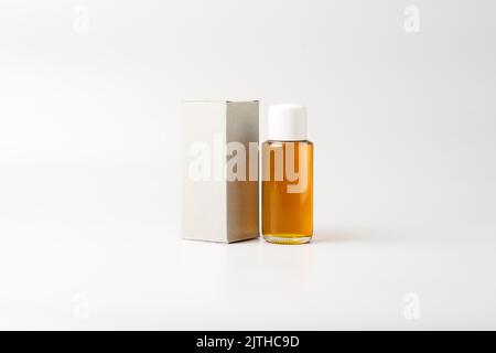 small oil bottle with white cap and blank box, mock-up template, isolated on gray background Stock Photo