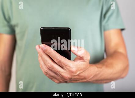 Man holding phone for checking social media, surfing Internet, looking through photos and news articles. Male hands with smartphone closeup. High qual Stock Photo