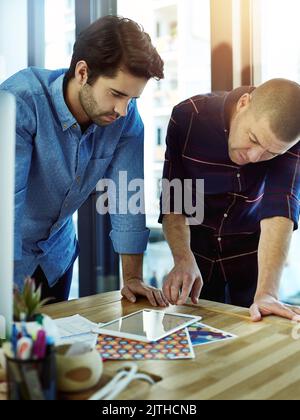 Using their time productively and effectively. two coworkers discussing something on a digital tablet. Stock Photo