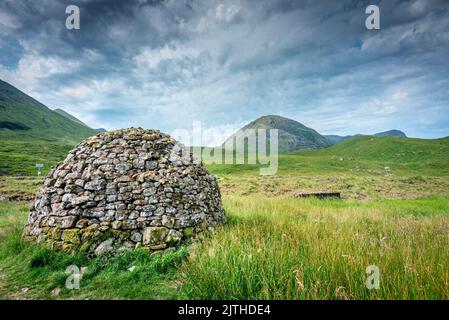 Beautiful dome shaped construction, built from nearby stones,once used as coffins for people of ancient Scotland,sitting amongst green summer grass of Stock Photo