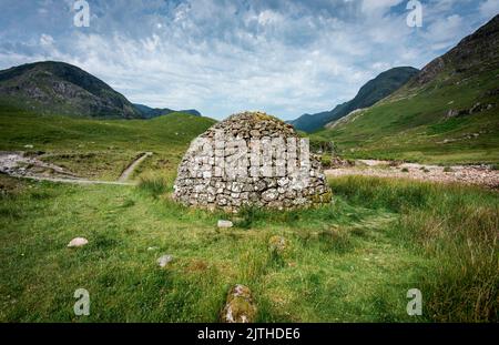 Beautiful dome shaped construction, built from nearby stones,once used as coffins for people of ancient Scotland,sitting amongst green summer grass of Stock Photo