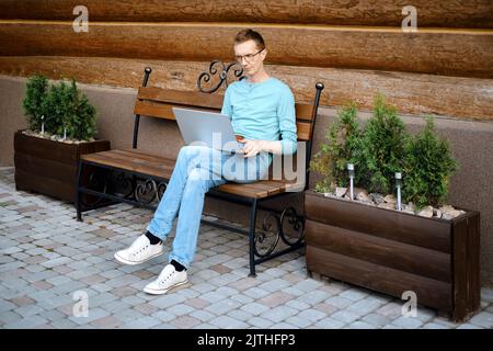 Middle aged man makes online order using laptop outdoors Stock Photo