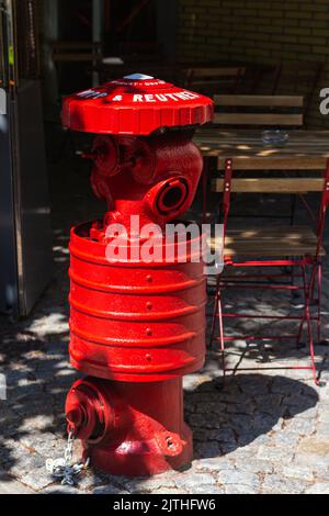 Old red fire hydrant in Kaliningrad street, sun rays shine brightly on metal equipment, copy space, selective focus. Preservation of architectural ind Stock Photo