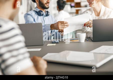 Close up of young diverse coworkers analyzing sales report while working together in the office Stock Photo