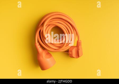 Orange extension Power Cord on the yellow background. Stock Photo