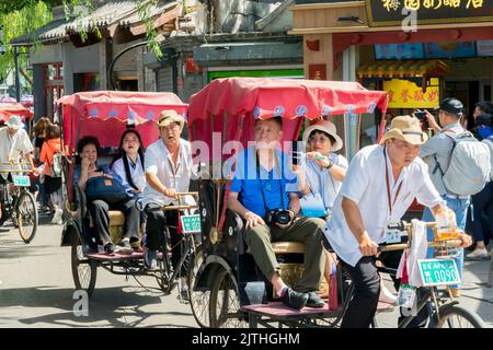 Chinese tourists are led in a rickshaw near Qianhai lake, Beijing. Stock Photo