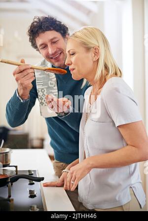 Seasoned generously with love. a happy couple cooking dinner together in their kitchen. Stock Photo