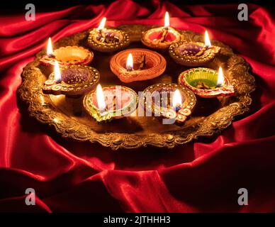Happy Diwali. Diya oil lamps lit on red color background, close up above view. Deepavali celebration. Hindu Festival of lights Stock Photo