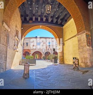 Palazzo Broletto gateway with vintage wooden ceiling, preserved frescoes and a view on the courtyard, Brescia, Lombardy, Italy Stock Photo