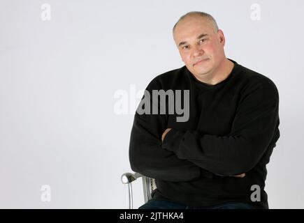 Portrait of a large middle-aged man on a gray background. Stock Photo
