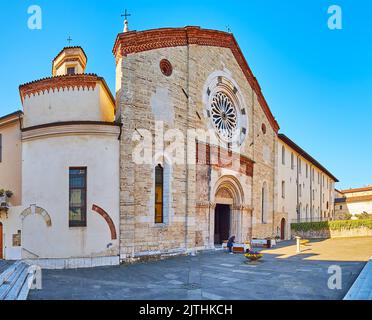 The medieval stone facade of the Romanesque San Francesco Church, decorated with carvings and rose window over the portal, Brescia, Italy Stock Photo