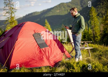 Man charges phone from solar panel while travel Stock Photo