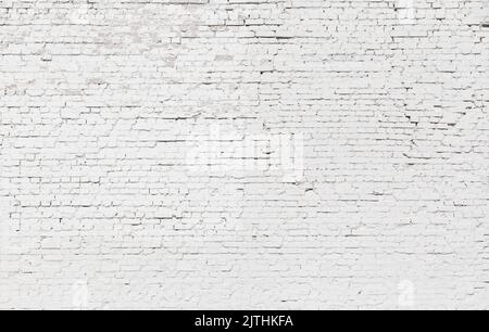 Uneven, aged and weathered brick wall, plastered and painted in white. Front view, full frame textured background. Copy space. Stock Photo