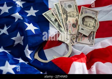 United States of America flag with handcuffs and a bundle of dollars. The concept of illegal banking operations in US currency. Stock Photo