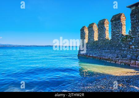 The bright azure Lake Garda with preserved medieval wall of Scaligero Castle, Sirmione, Italy Stock Photo