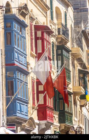 Malta flags waving from the colorful traditional maltese balconies in Valletta Stock Photo