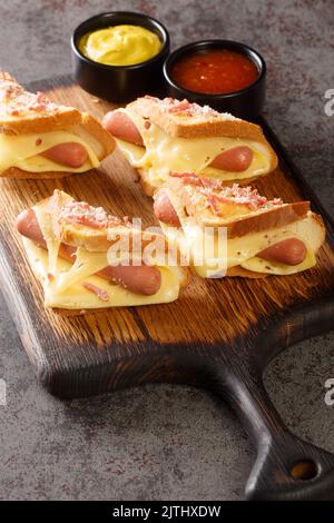 Fried crispy bread with sausage and melted cheese closeup in the wooden board on the table. Vertical Stock Photo