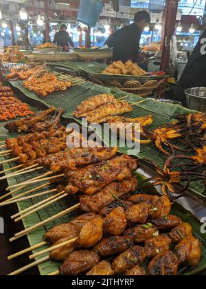 Barbequed chicken, prawns, octopus and lobster on bamboo skewers at a street food stall in Bangkok, Thailand Stock Photo