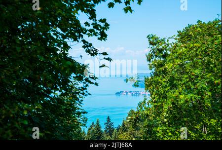 Germany, Lindau island houses at bodensee lake seen through green window of trees from pfänder mountain Stock Photo