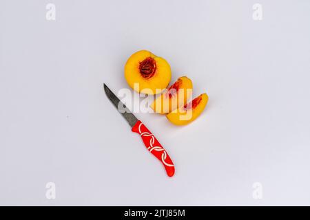Peach fruit sliced with knife on white isolated background Stock Photo