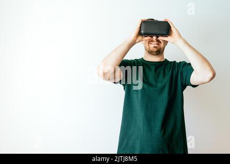 A smiling Caucasian young man wearing Virtual Reality Glasses on a white background with copyspace Stock Photo