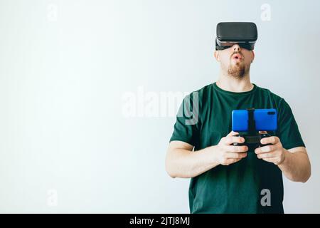 A surprised Caucasian young man wearing Virtual Reality Glasses on a white background with copyspace Stock Photo