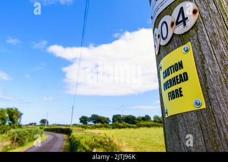Sign on a wooden telephone pole warning people that the pole is carrying fibre optic cable. Stock Photo