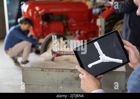 31 August 2022, Lower Saxony, Osnabrück: An industrial computer scientist scans an axle stub from a Porsche Junior 108 tractor for illustration purposes using a tablet and software that relies on artificial intelligence. Industrial engineer Tobias Dreesbach (back) from the Research Center for Artificial Intelligence (DFKI) looks through augmented reality (AR) glasses. In the future, the Research Center for Artificial Intelligence (DFKI) and the Museum of Industrial Culture (MIK) want to work together to prepare formats for a broad audience. The focus will be on industrial history and current r Stock Photo