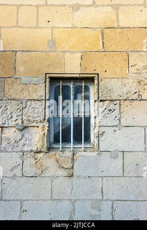 Security bars on a window in a beautiful textures natural stone wall. High quality photo Stock Photo