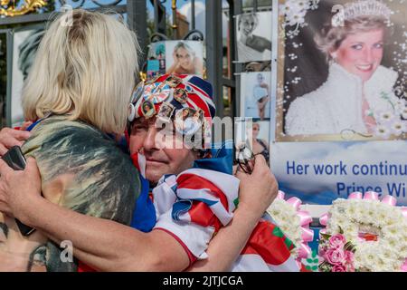 Kensington Palace, London, 31st August 2022.   Royal Fans Maria Scott and John Loughrey share a comforting hug at the Kensington Palace Gates on the 25th Anniversary of the death of Diana, Princess of Wales.  The Princess was killed in a car crash in Paris on this day in 1997.  Amanda Rose/Alamy Live News Stock Photo