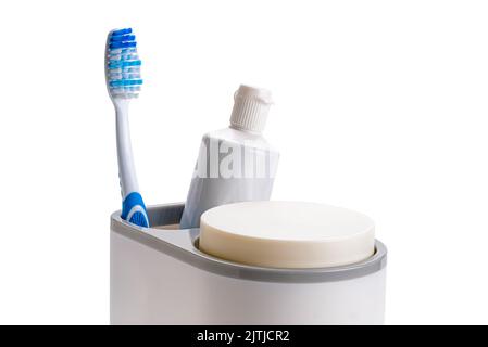 Single new blue handle toothbrush and a tube of toothpaste in plastic holder isolated on white background with clipping path. Stock Photo